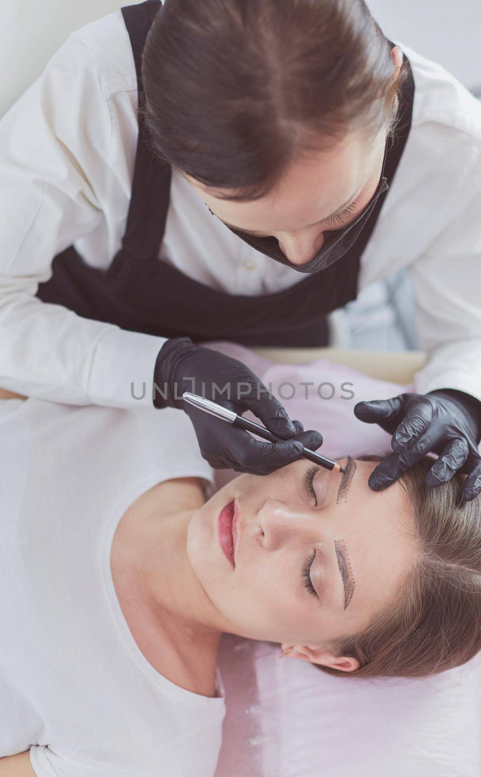 Cosmetologist applying permanent make up on eyebrows by lenets