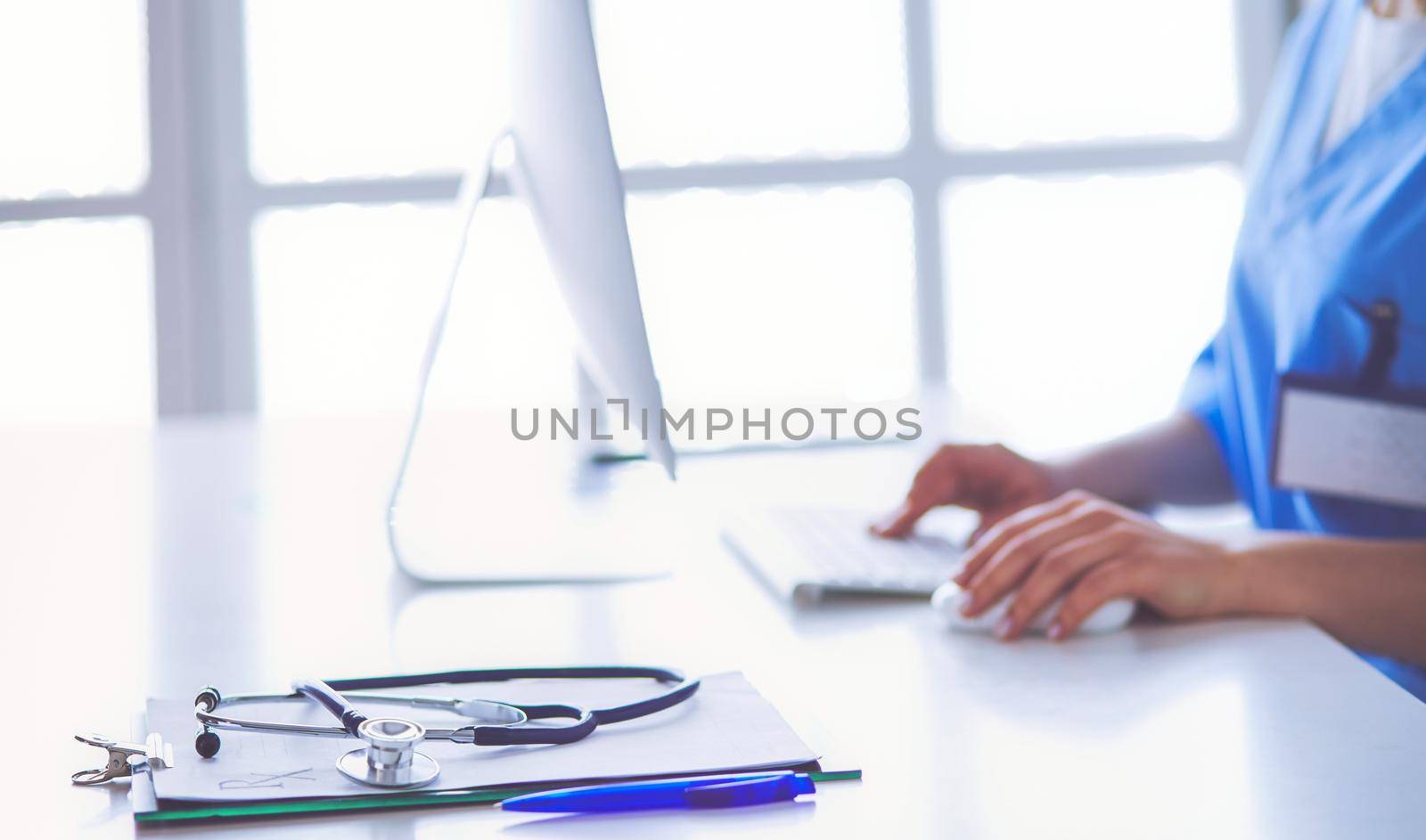 Beautiful young smiling female doctor sitting at the desk