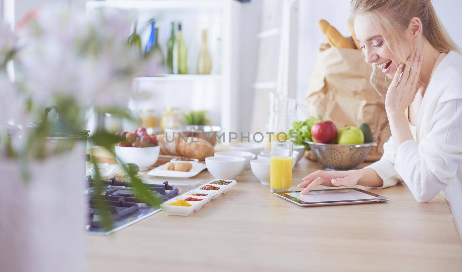 Beautiful young woman using a digital tablet in the kitchen.