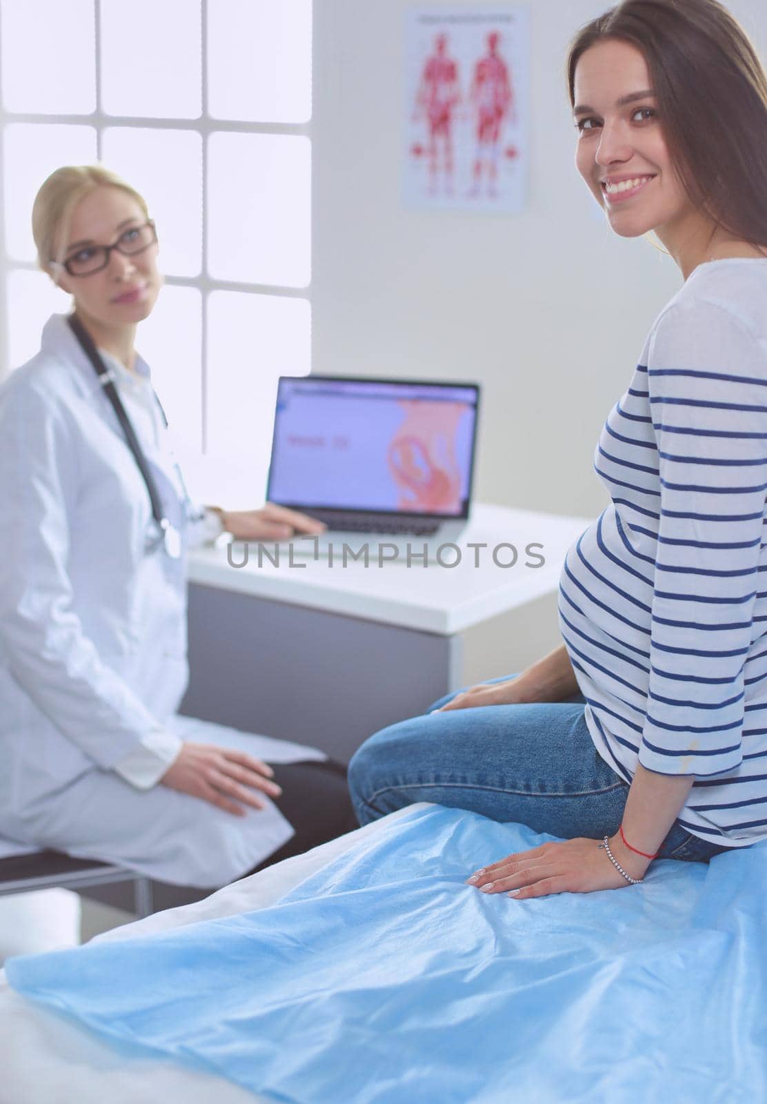 Beautiful smiling pregnant woman with the doctor at hospital.