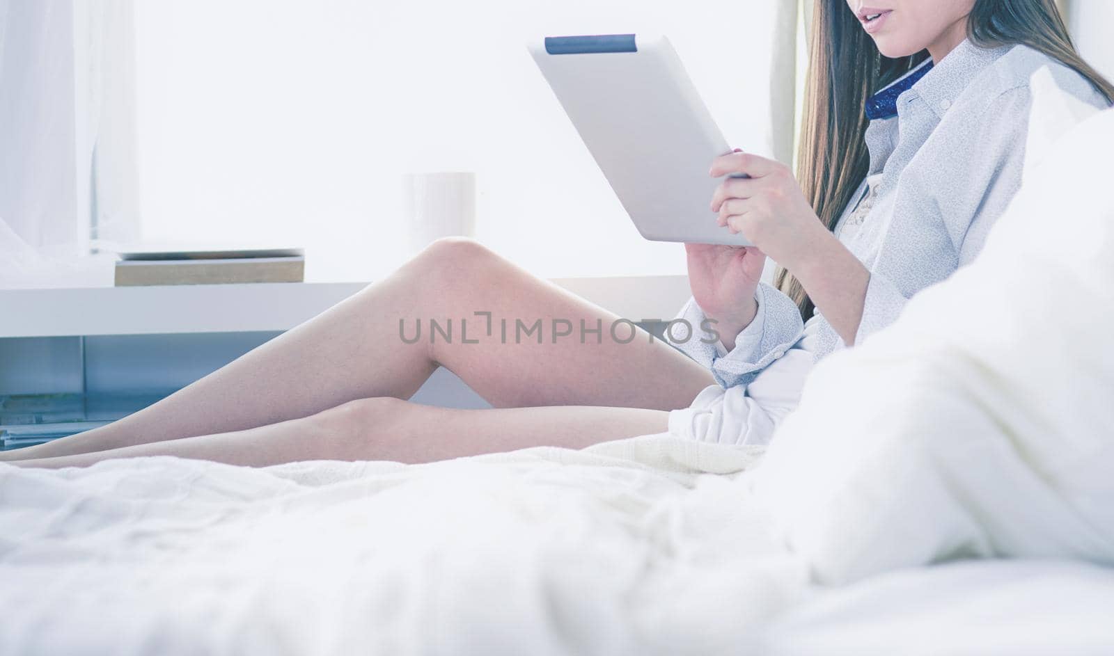 Woman sitting in bed reading a book and having breakfast.