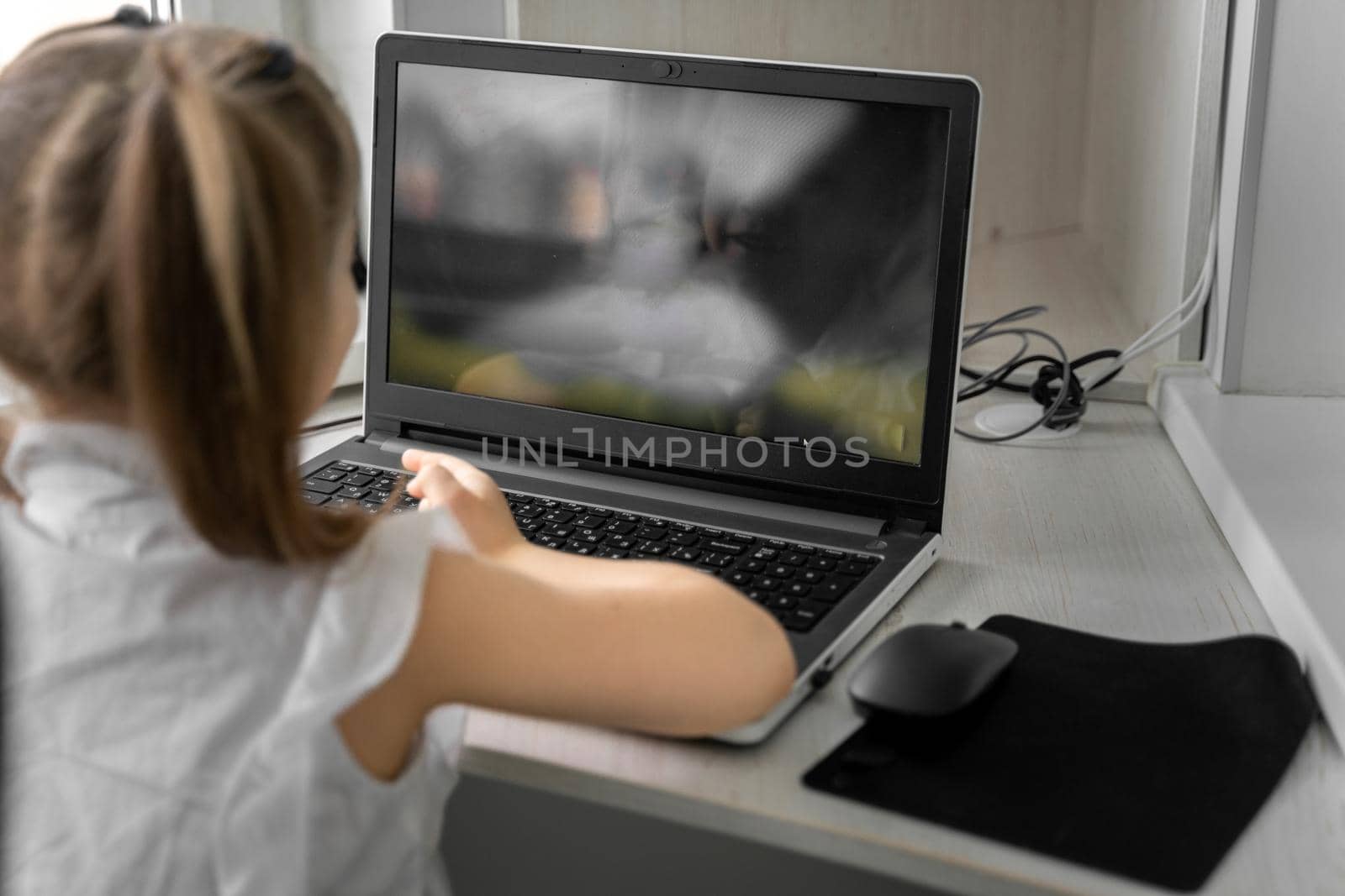 cute little caucasian girl studying online at home