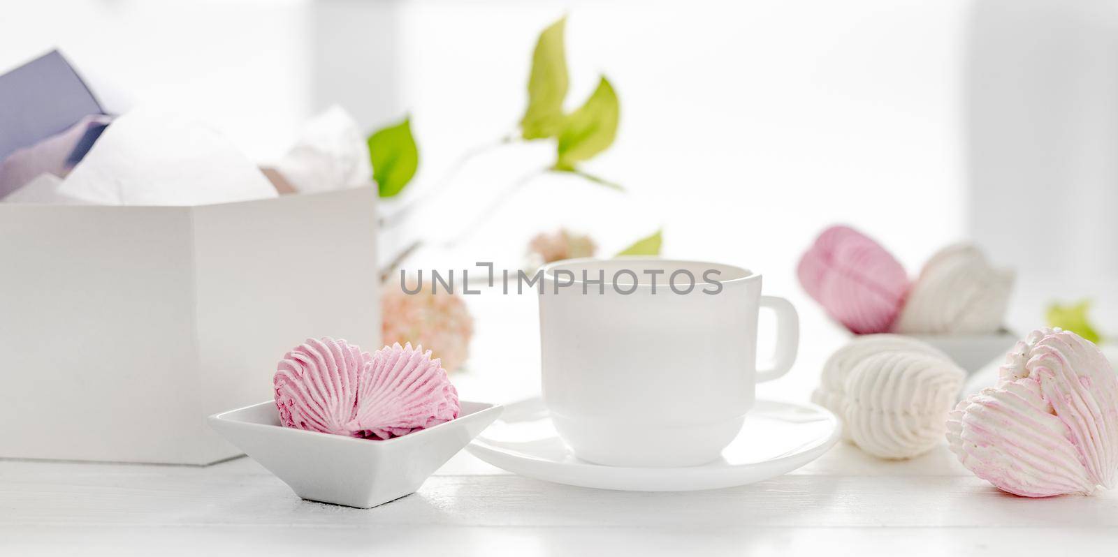Heart shape marshmallows pink and white color and cup with tea. Craft desert sweets on table