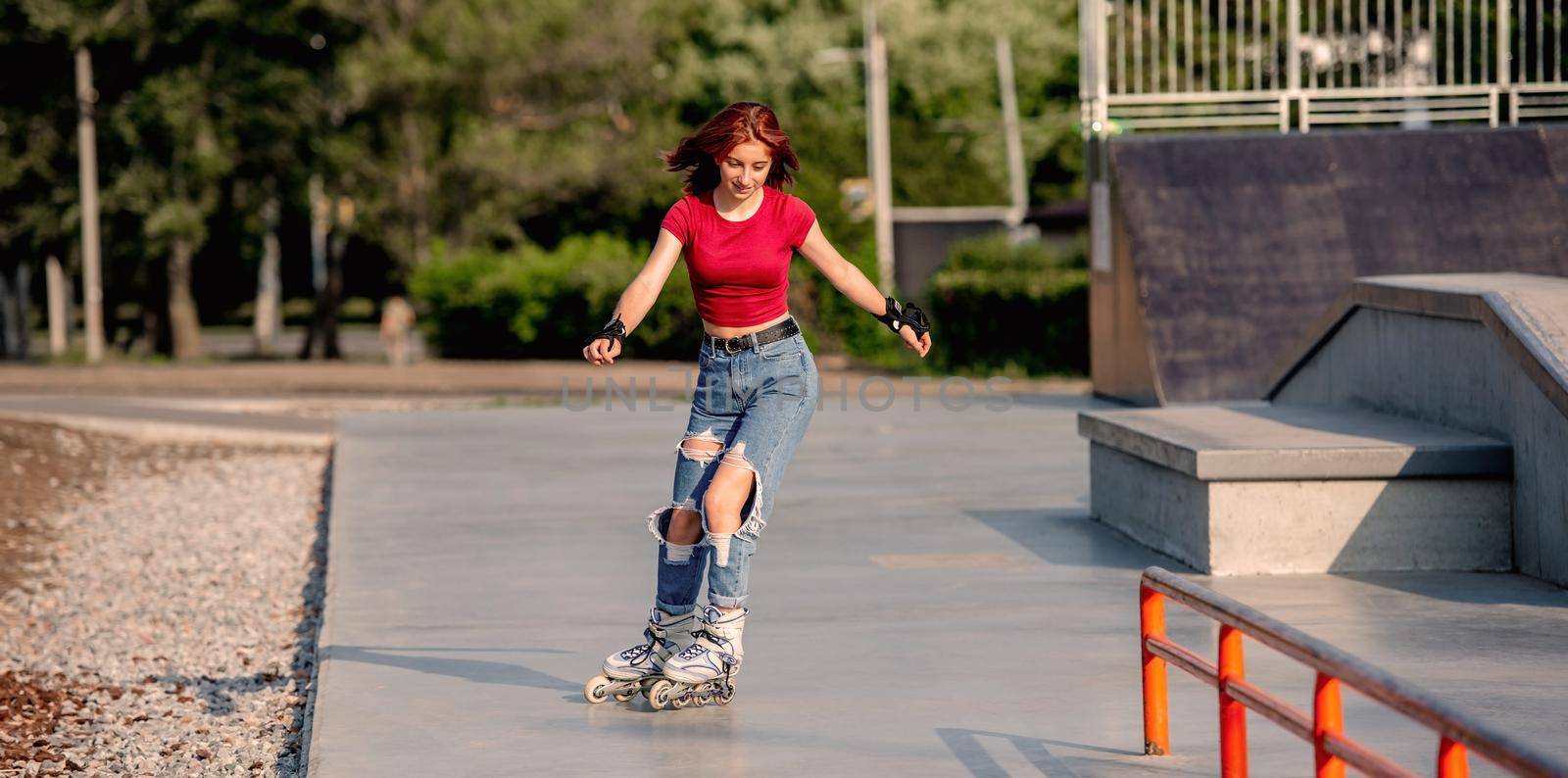 Pretty girl on roller skates practicing riding in the city in sunny day. Female teenager rollerblading at summer outdoors
