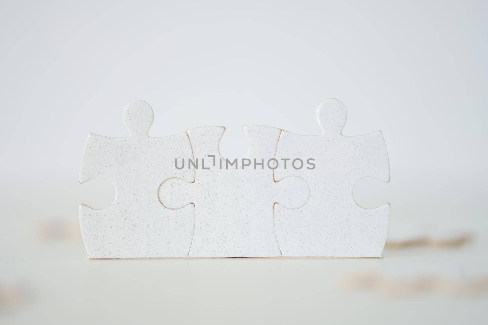 Close-up of white pieces of puzzle put together, connected parts, lined details. Missing parts of whole picture. Puzzle game, jigsaw, entertainment concept