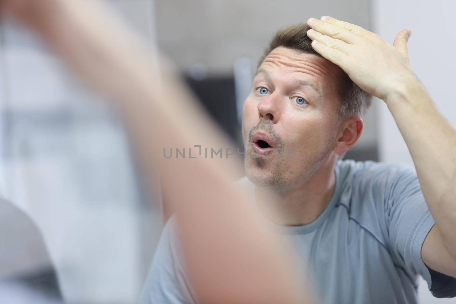 Portrait of middle aged man touch his new hairstyle, look in mirror reflection. Stylish haircut, man like appearance. Morning, treatment, image concept