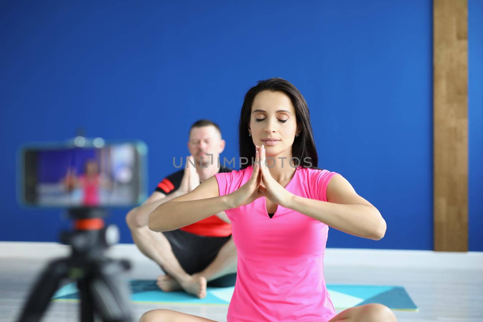 Portrait of people perform asana on mat in studio, record video for social media channel. Morning ritual for body and soul health. Course, content concept