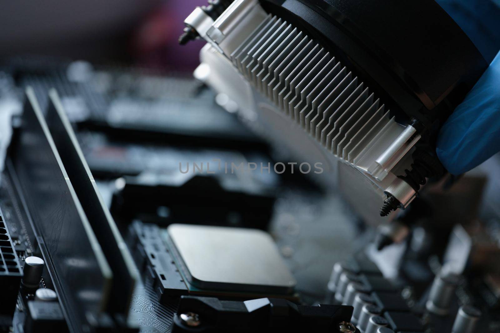 Close-up of someone install cooler fan with copper tubes on computer processor, sterile glove for work. Computer motherboard with parts. Technology concept