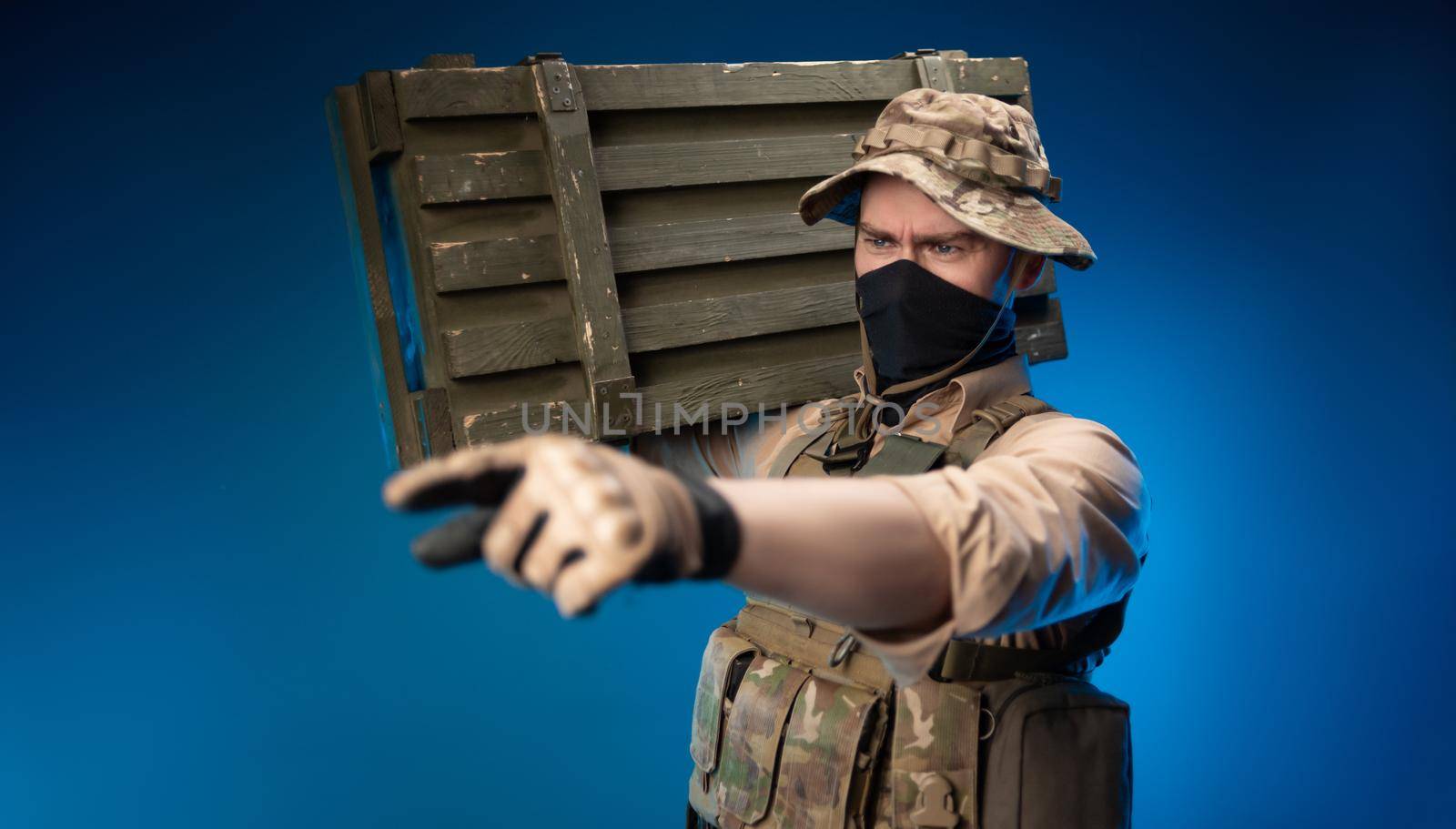 an army soldier in military clothes with a box of ammunition on his shoulder by Rotozey