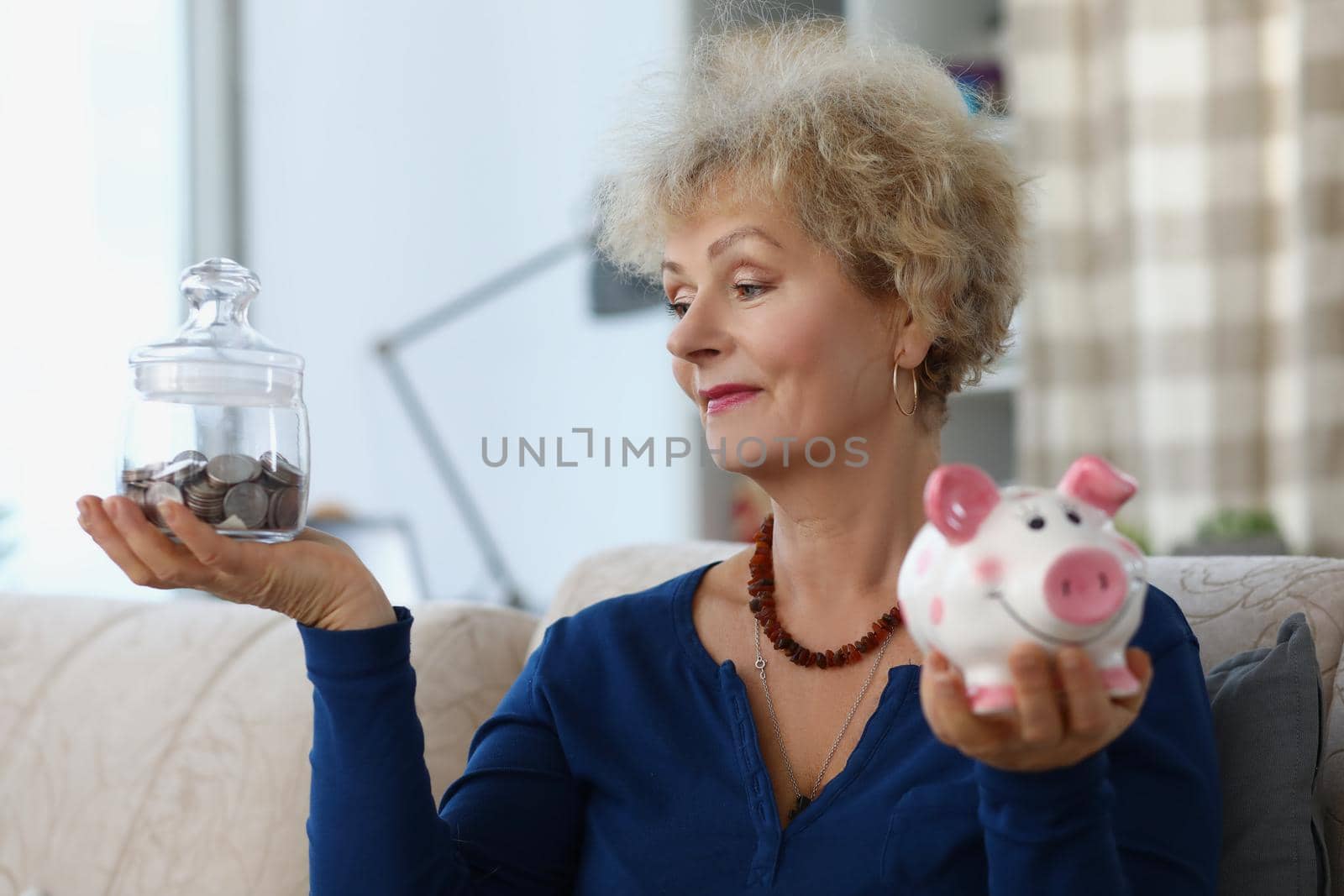 Portrait elderly female hold glass container with saved money for retirement and piggybank. Financial education, saveup for future, family budget concept