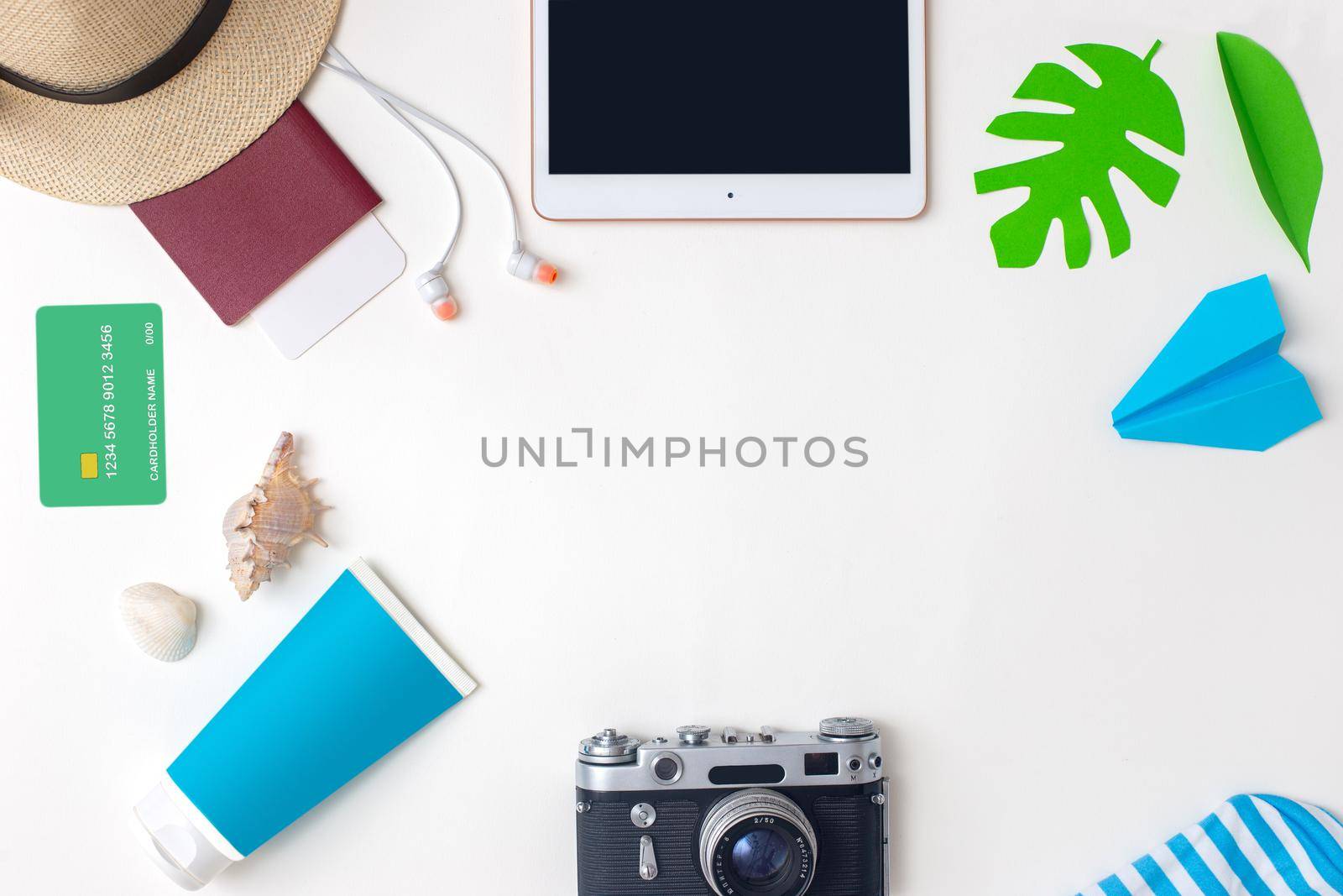 Summer travel accessories set top view on white background : passport, camera, straw hat, digital tablet, sunscreen, headphones, credit card , seashell, paper airplane . Copy space.