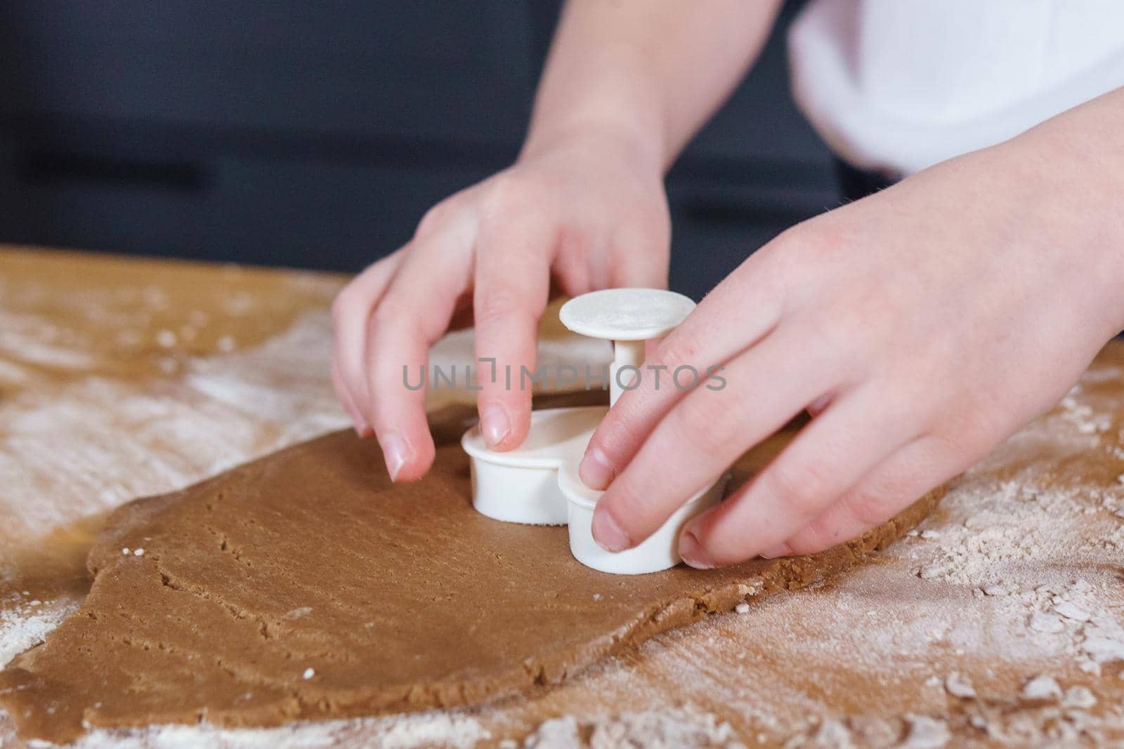 A little girl makes heart-shaped cookies from rye dough. The concept of Valentine's Day and healthy baking. Cooking cookies in close-up.