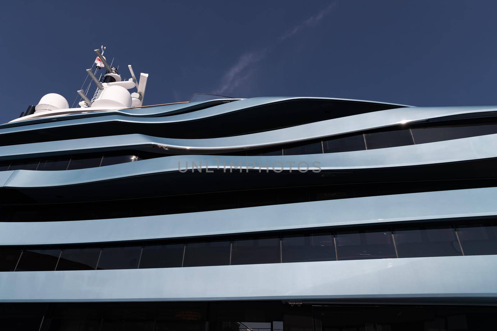 Bottom view of decks of huge yacht of blue color at sunny day, glossy board of the motor boat, sun reflection on glossy board, blue sky is on background. High quality photo