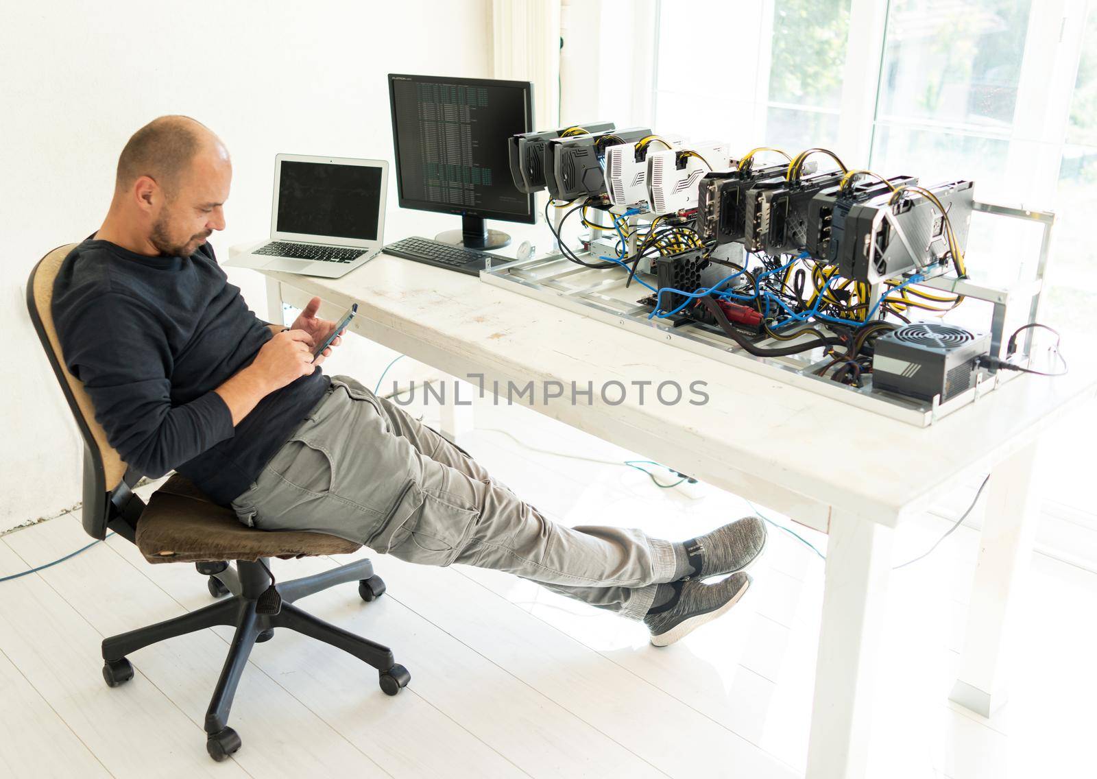 Young programmer adjusting cryptocurrency mining rig to optimal operational settings. High quality photo