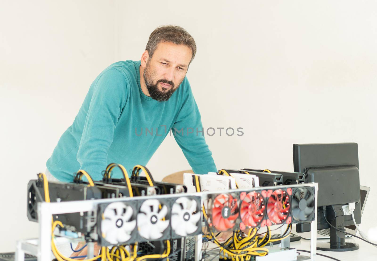 Young programmer adjusting cryptocurrency mining rig to optimal operational settings. High quality photo