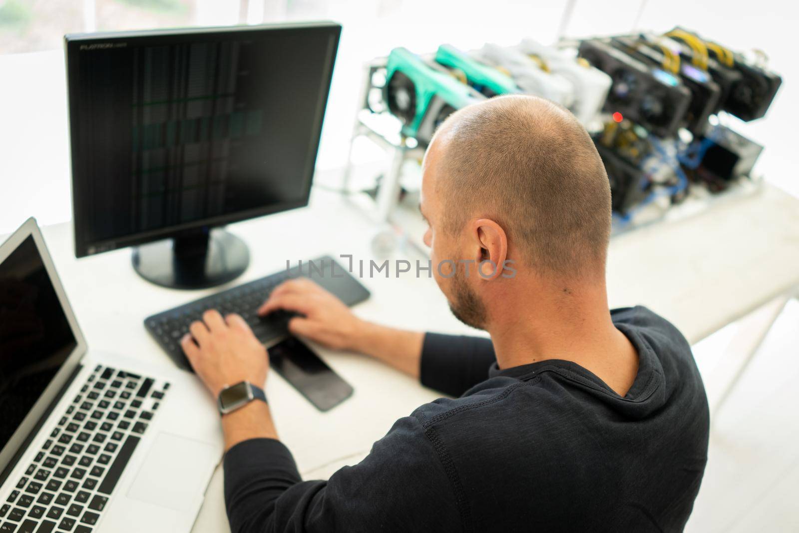Young programmer adjusting cryptocurrency mining rig to optimal operational settings. High quality photo