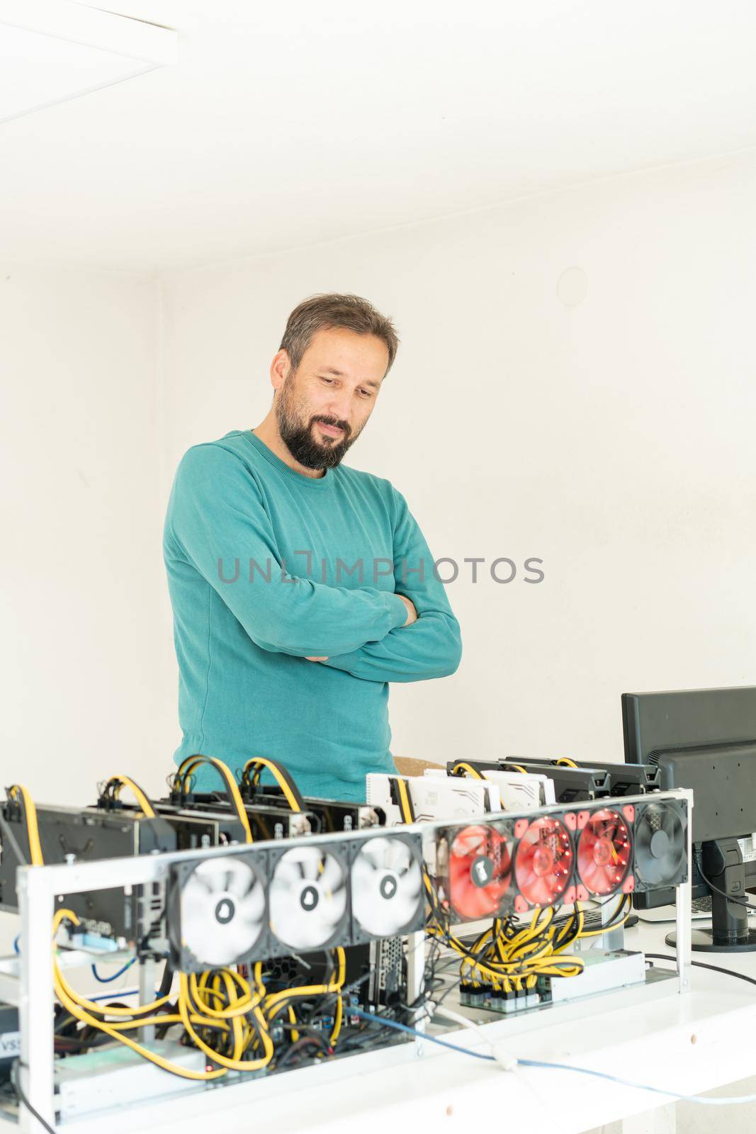 Young programmer adjusting cryptocurrency mining rig to optimal operational settings by Zurijeta