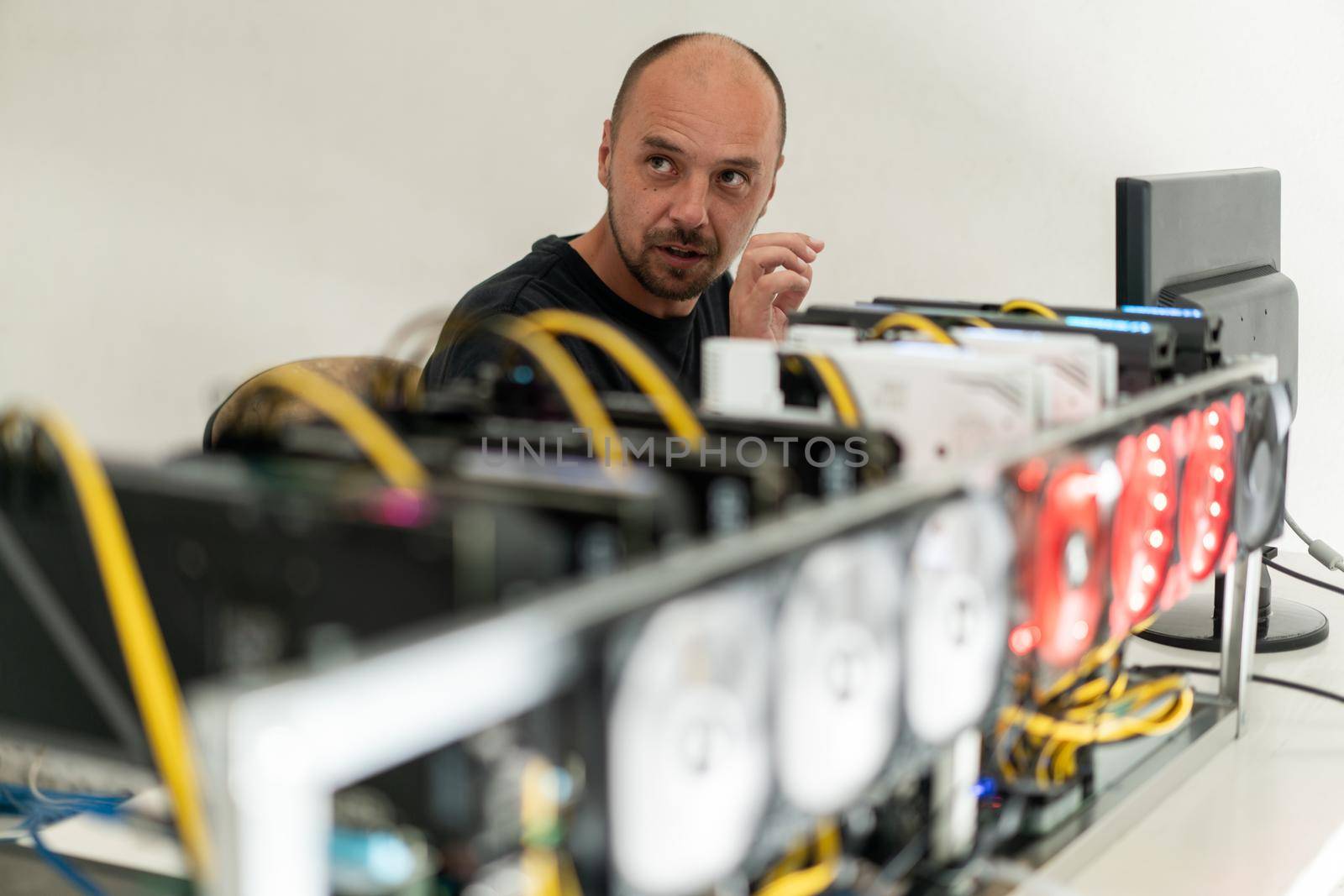 Young programmer adjusting cryptocurrency mining rig to optimal operational settings. High quality photo