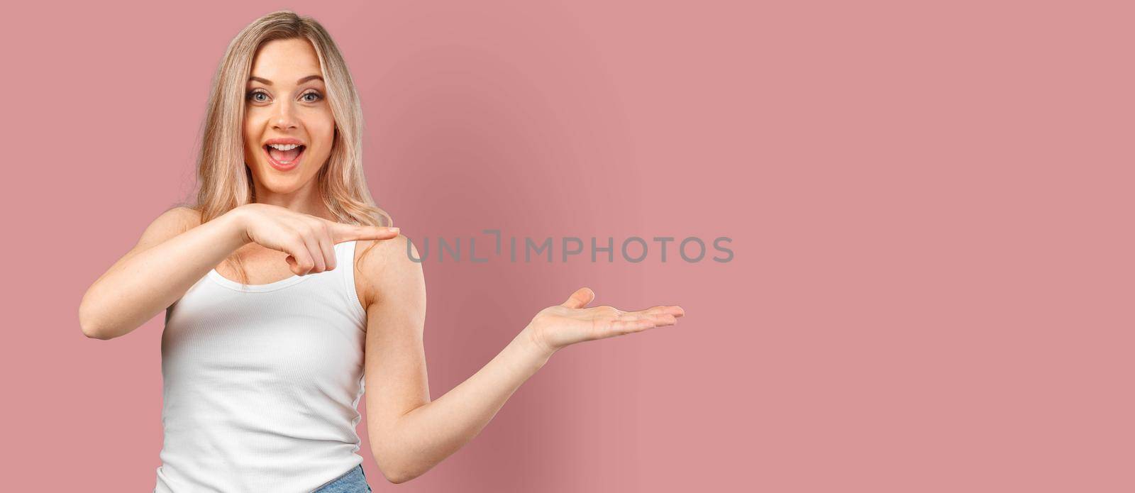 Young smiling woman pointing to copy space isolated on color background, close up