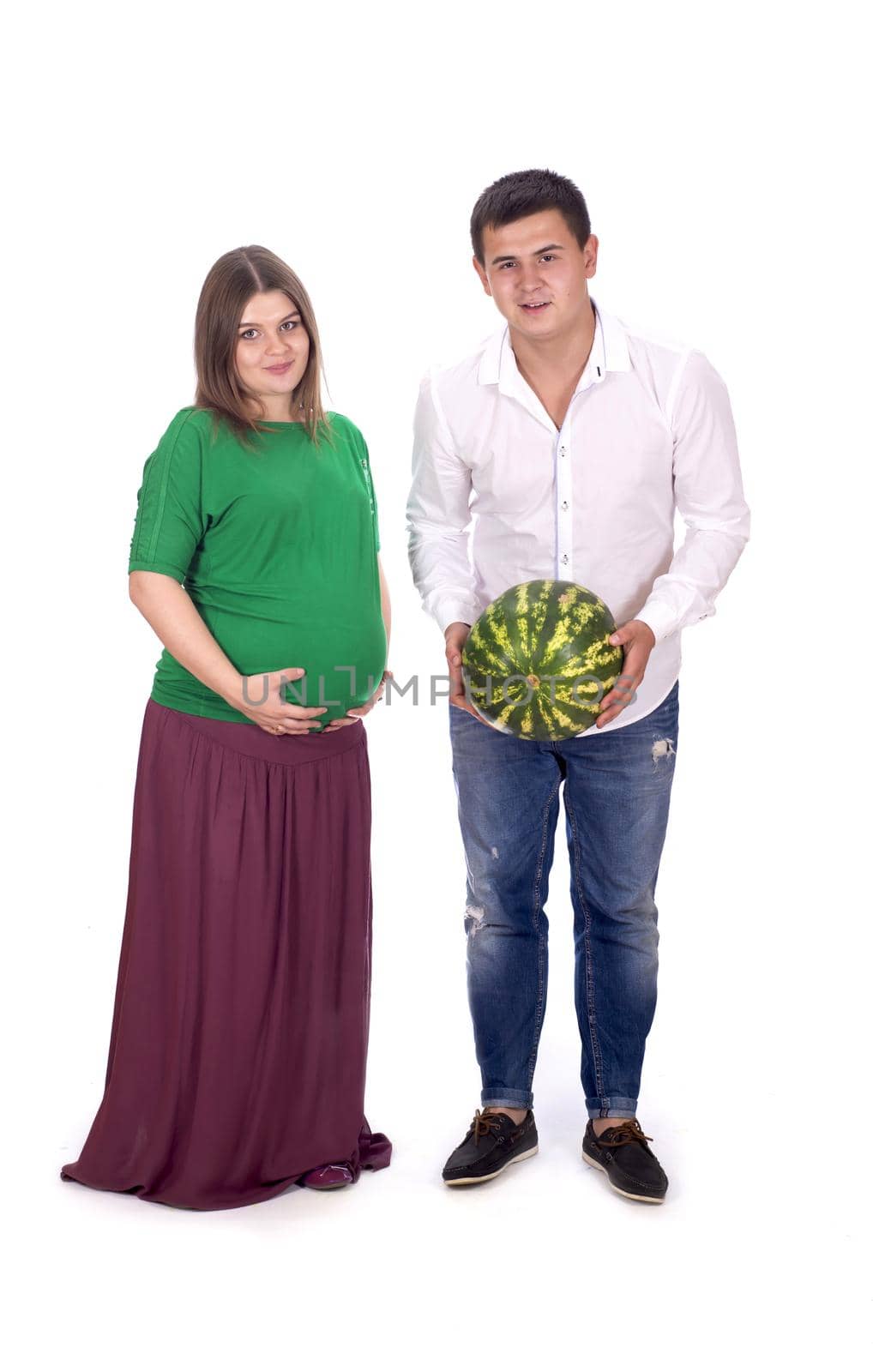 A man and a pregnant woman are holding a large watermelon in their hands. isolated on white background by aprilphoto
