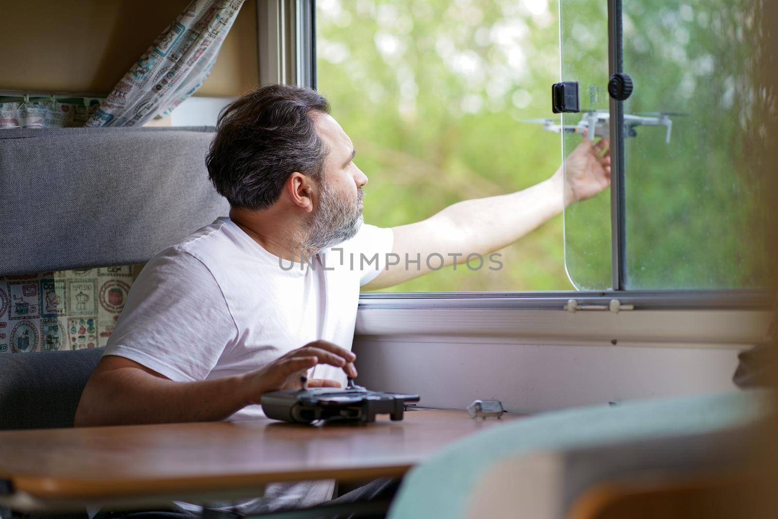 motorhome travel concept. Man controling a drone.a man controls a drone from the window of a motorhome by aprilphoto