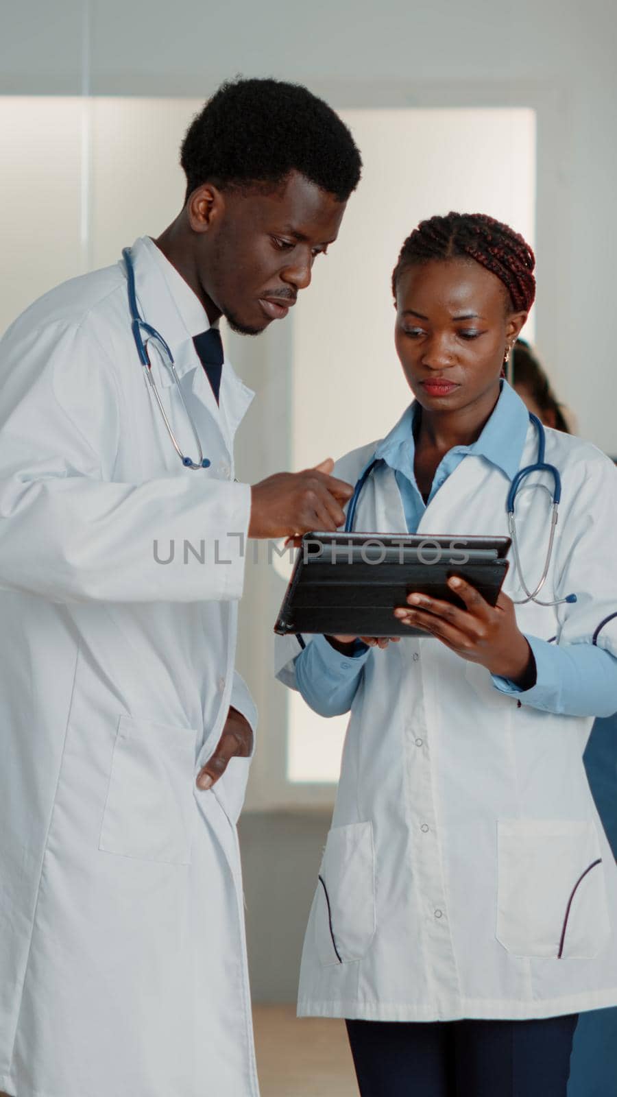 Doctors doing teamwork with digital tablet to find medicine against disease. Man and woman with gadget looking at screen to find healthcare information about treatment. Medical care