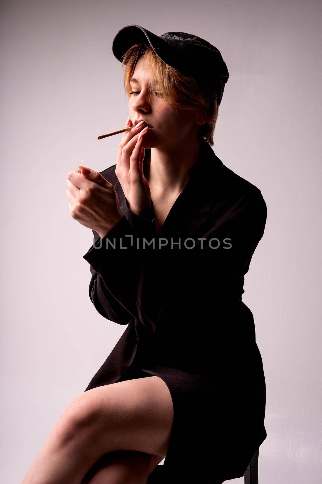A girl lights a cigarette in a cap in a black suit on a white background girl cigarette smoke female isolated, from design face in style from beautiful nicotine, lips habit. 20 party, by 89167702191