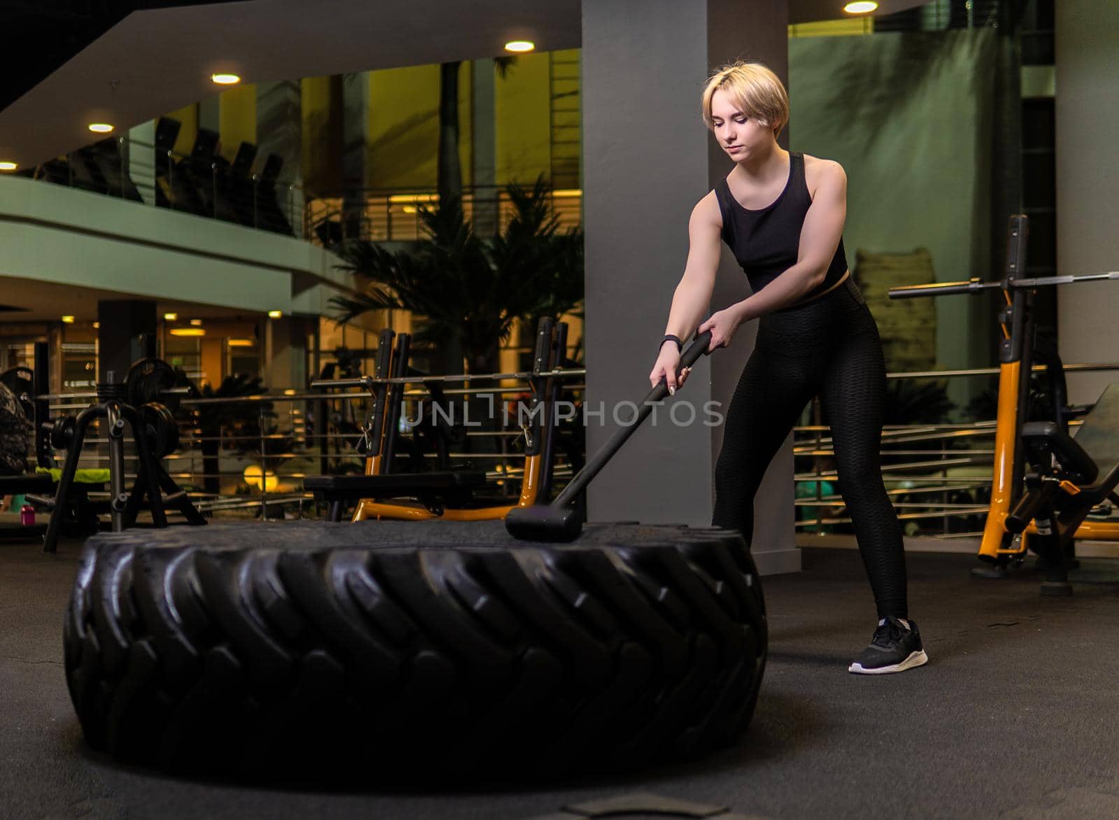 Wheel with sledgehammer girl stands tire active exercise, for sport strong in body young lifestyle, urning leaning. Posing woman lights, rest