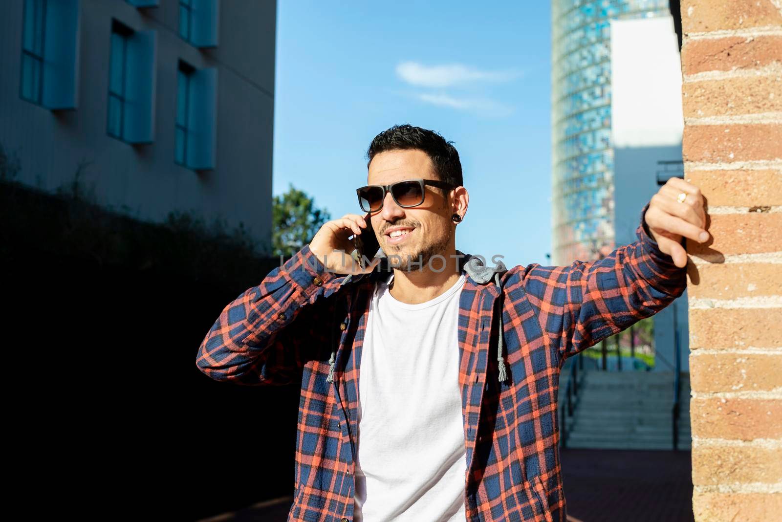 Young male smiling and talking on mobile phone outside