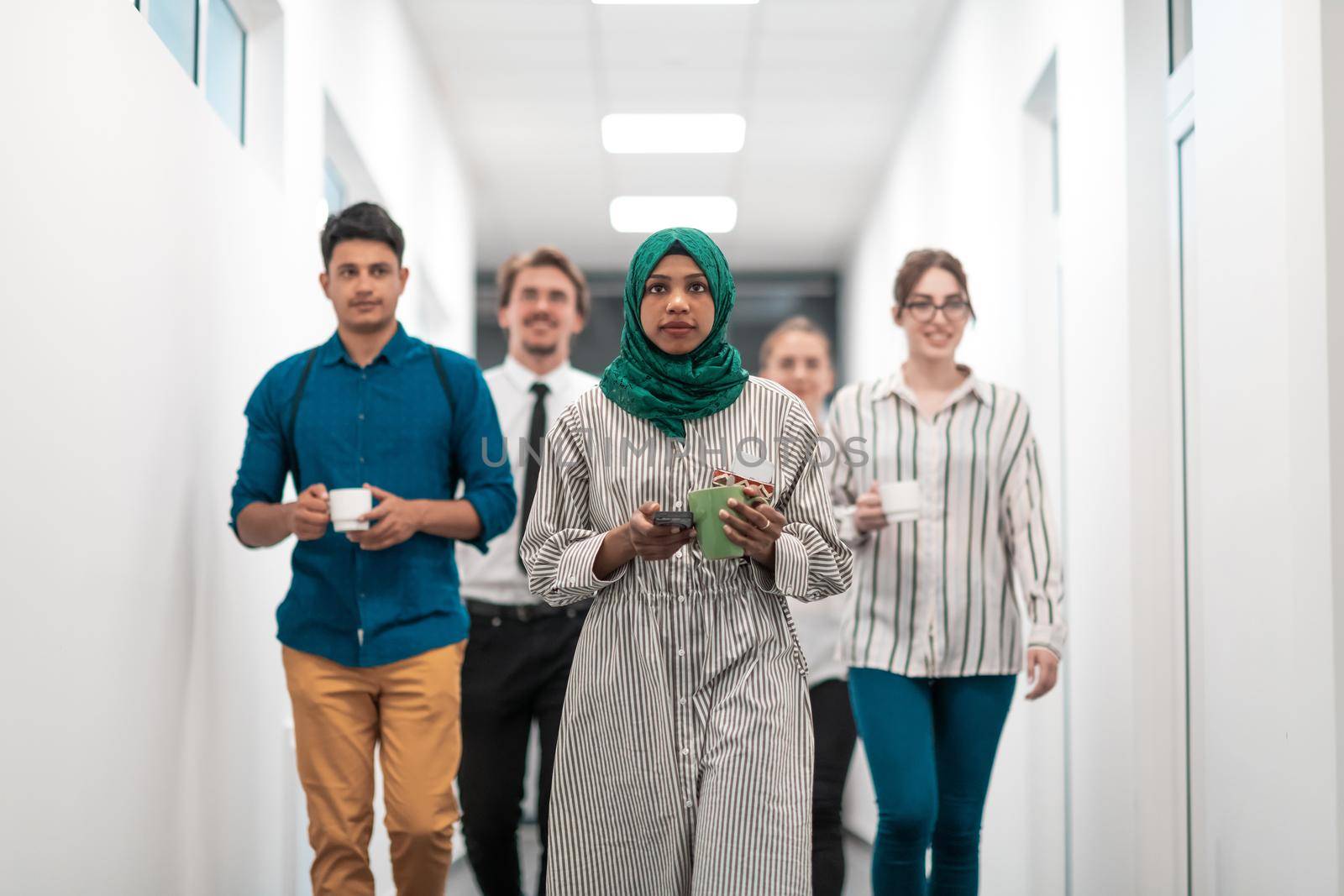 Multi-ethnic startup business team walking through the hallway of the building while coming back from a coffee break. High-quality photo