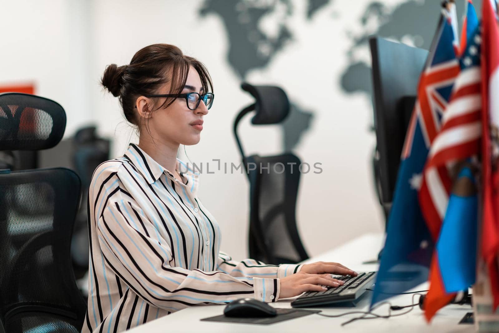 Casual business woman working on desktop computer in modern open plan startup office interior. Selective focus by dotshock