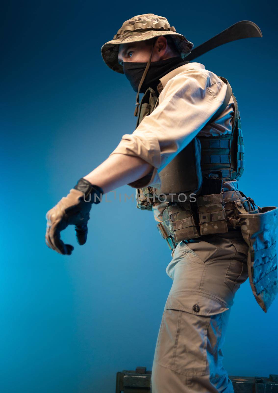 an army soldier in military clothes swings to strike with a machete in his hand