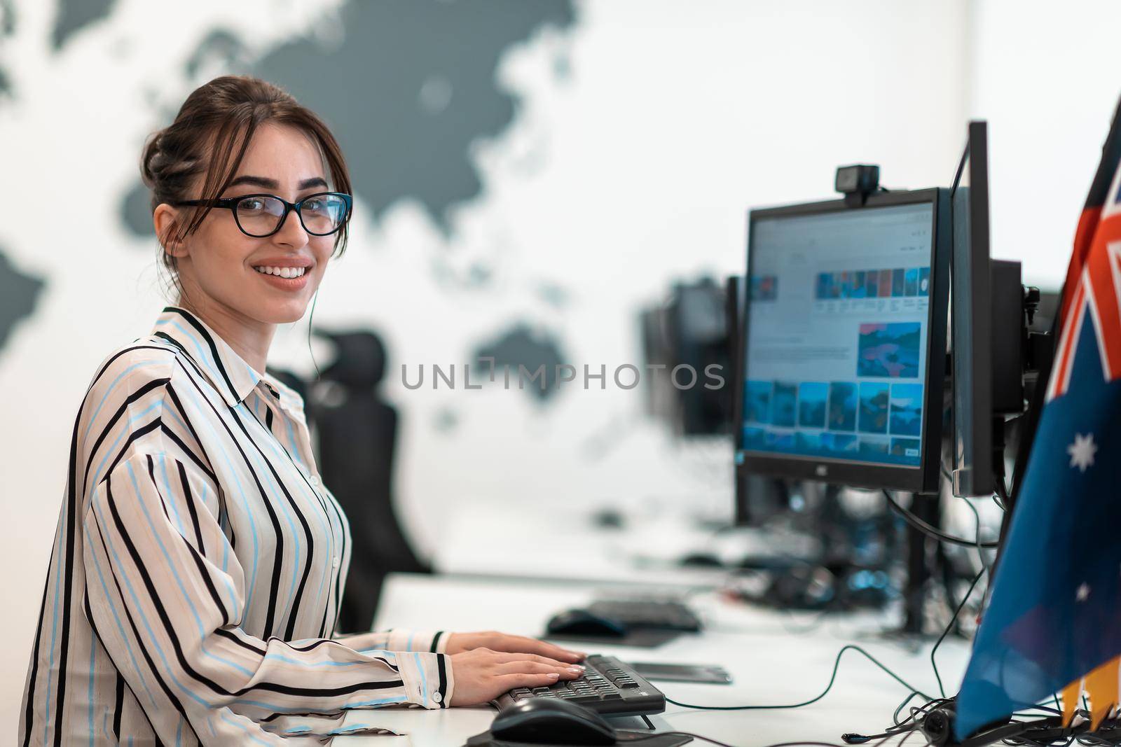 Casual business woman working on desktop computer in modern open plan startup office interior. Selective focus by dotshock