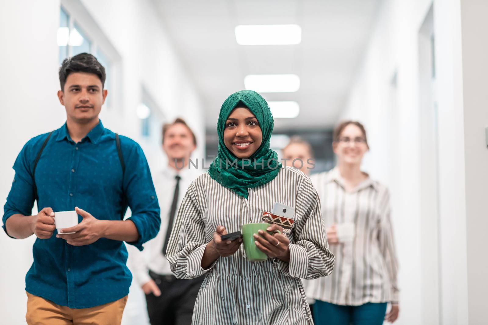 Multi-ethnic startup business team walking through the hallway of the building while coming back from a coffee break. High-quality photo