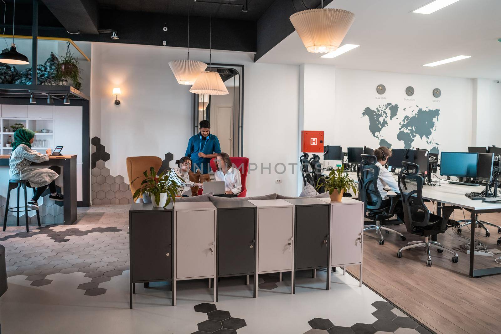 Group of casual multiethnic business people taking break from the work doing different things while enjoying free time in relaxation area at modern open plan startup office by dotshock