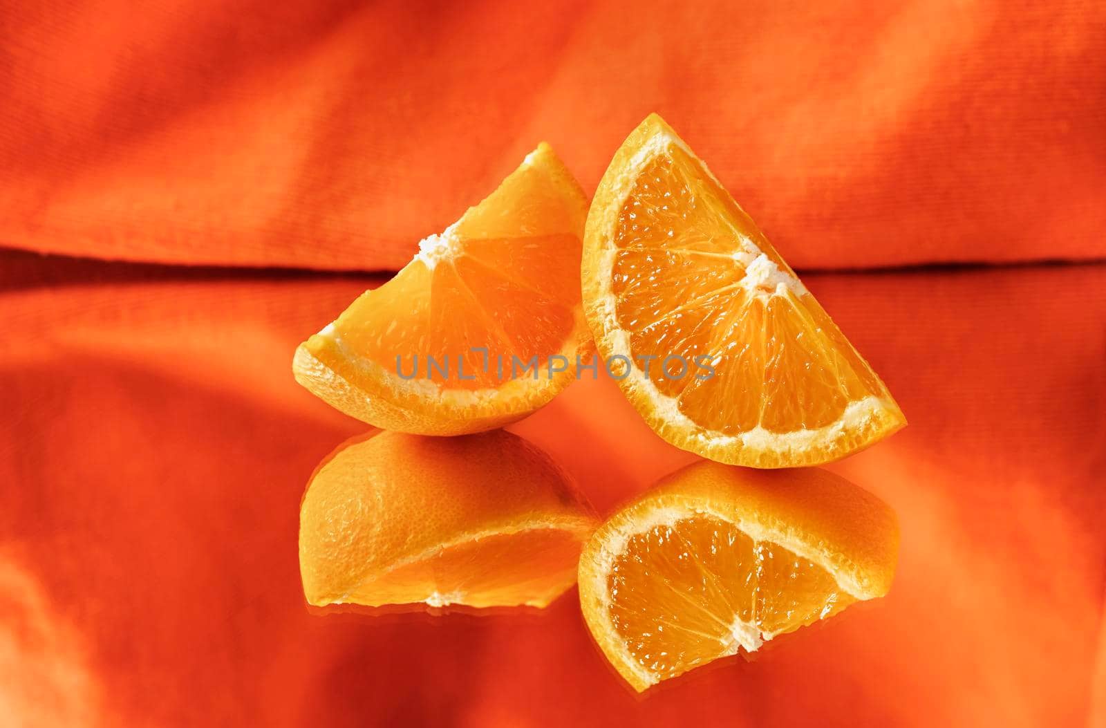 Slices of orange fruit on mirror on orange background , mirror reflection , 