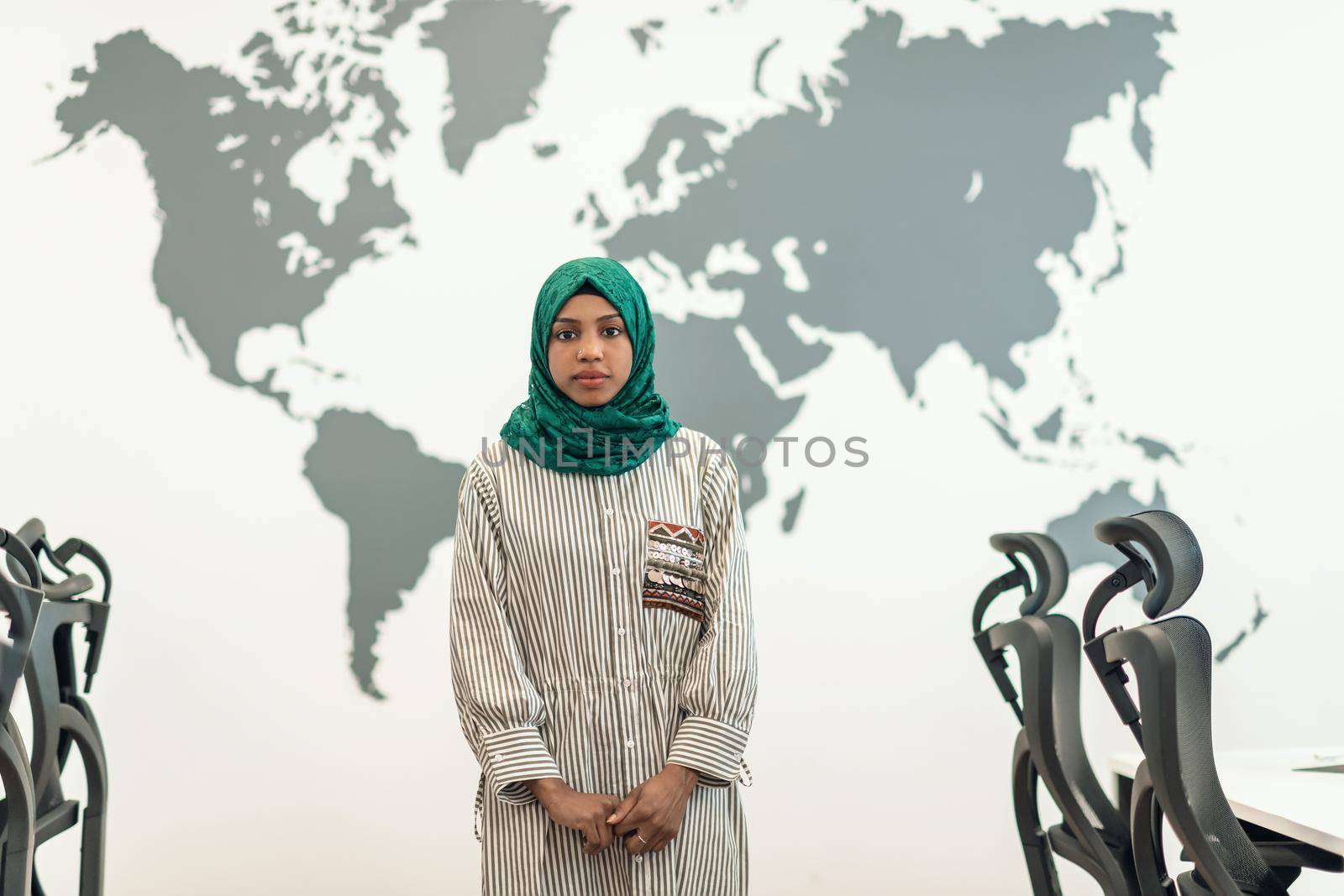 Portrait of muslim female software developer with green hijab standing at modern open plan startup office by dotshock