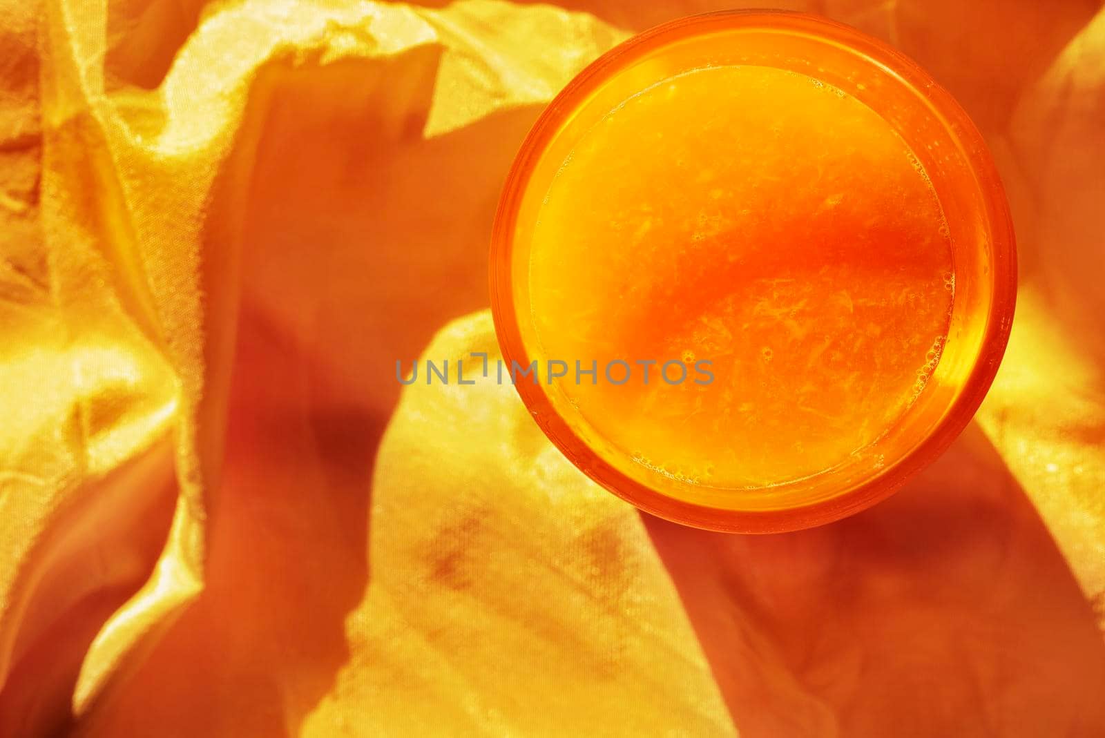 Bright glass of orange juice on orange background 