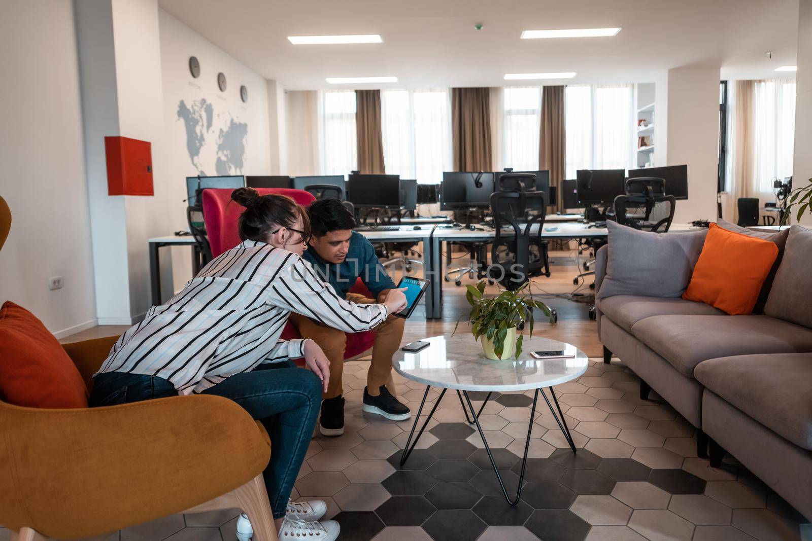 Group of casual multiethnic businesspeople taking a break from the work doing different things while enjoying free time in relaxation area at modern open plan startup office. High-quality photo