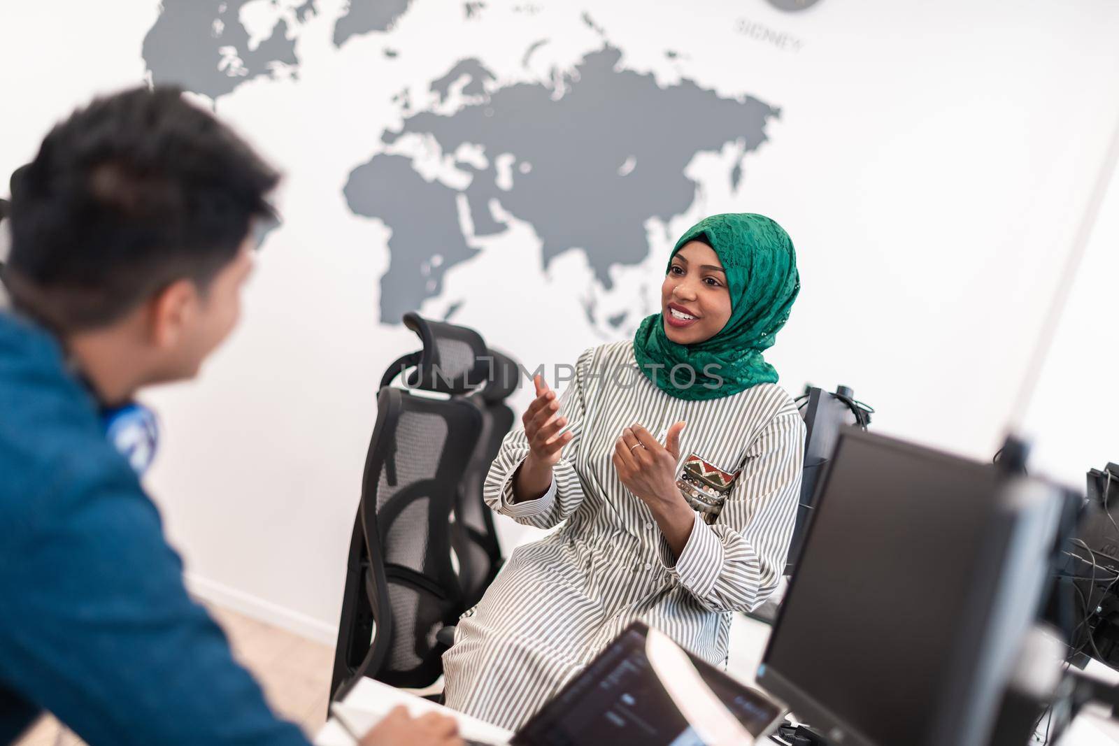 Multiethnic startup business team Arabian woman wearing a hijab on meeting in modern open plan office interior brainstorming, working on laptop and desktop computer. Selective focus. High-quality photo