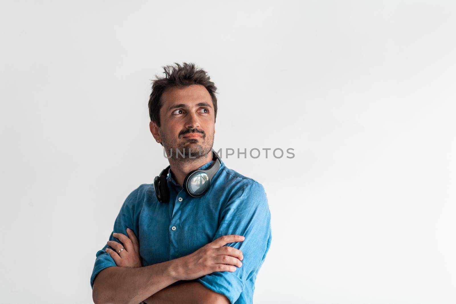 Formal business male portrait. A confident successful casual businessman or manager stands in front of a white background, arms crossed, looking directly at the camera and smiling friendly. High quality photography by dotshock