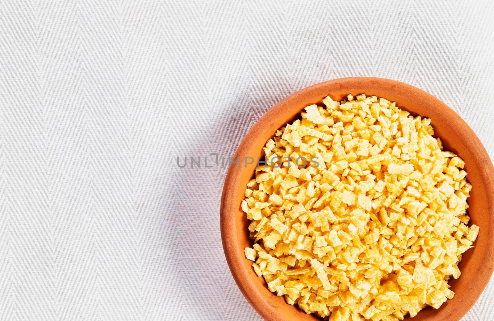  Small flat squares  egg pasta called grattini in plate on white background,yellow  pasta with rough surface 