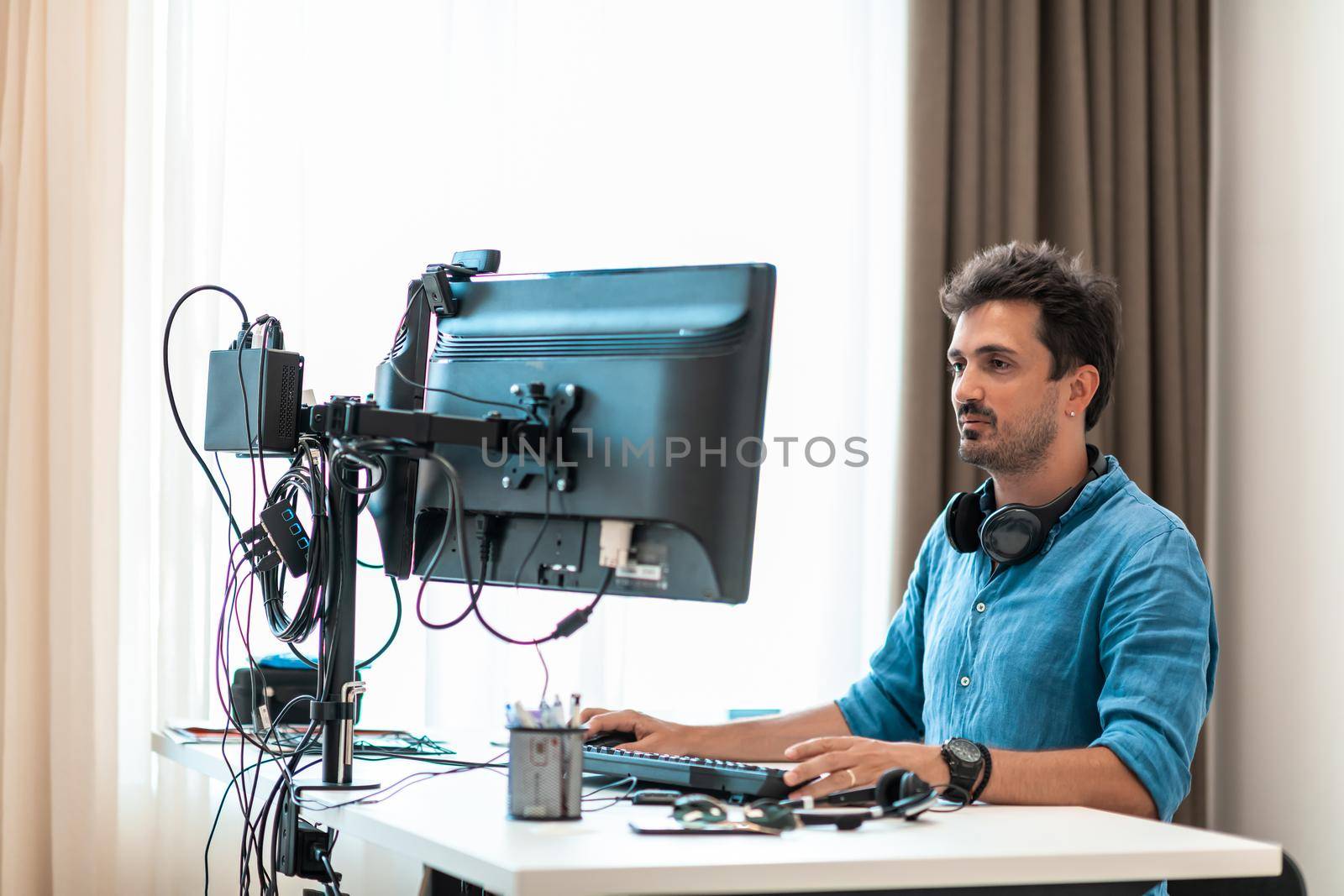 Casual man working on desktop computer in modern open plan startup office interior. Selective focus by dotshock