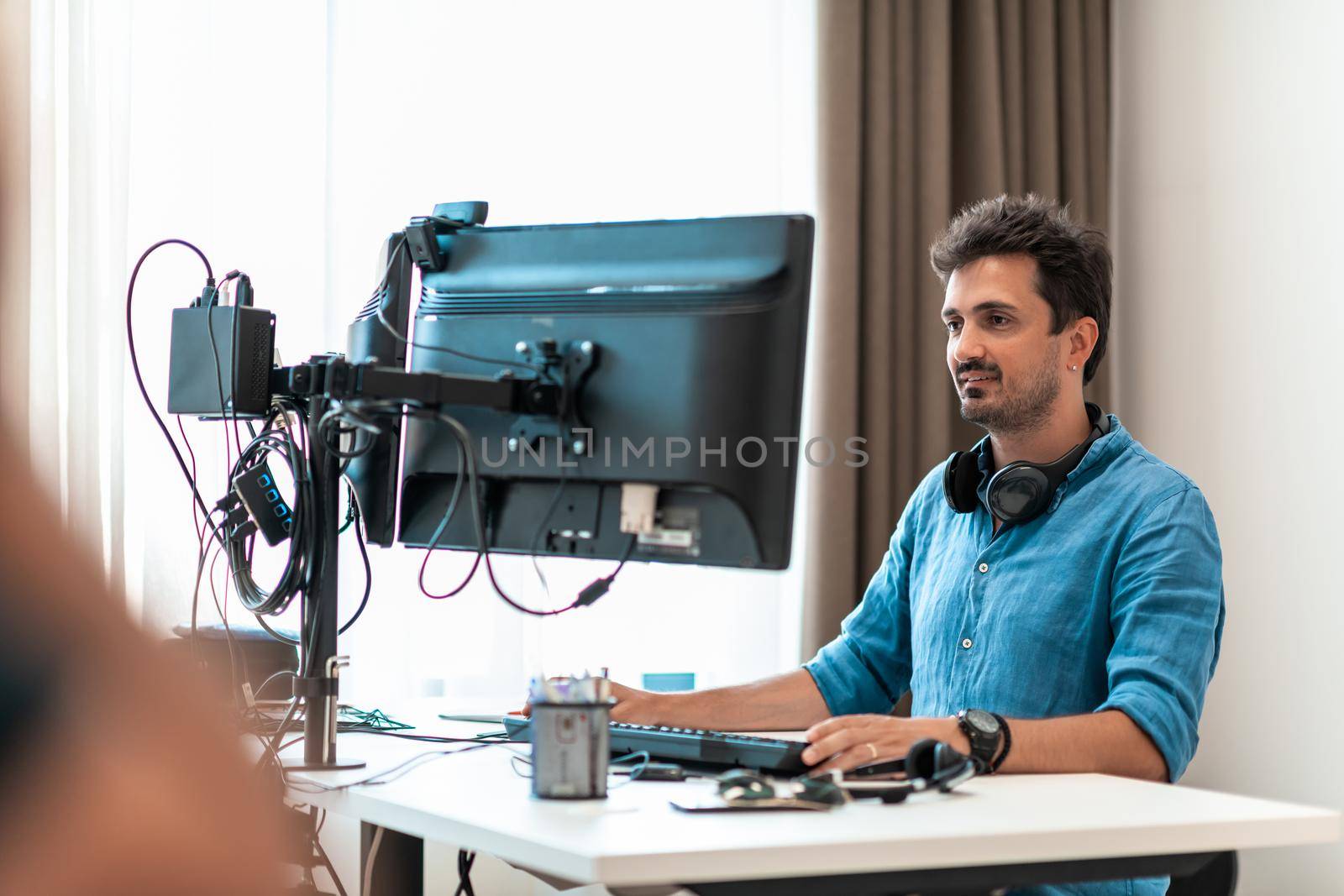 Casual man working on desktop computer in modern open plan startup office interior. Selective focus by dotshock