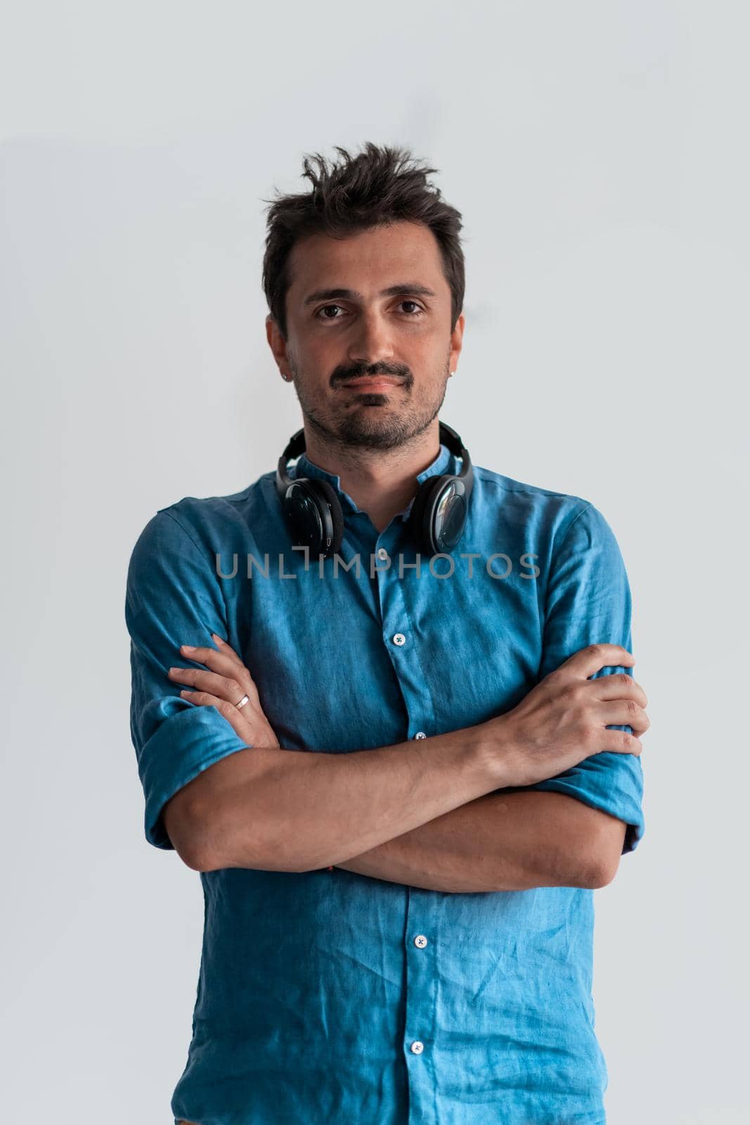 Formal business male portrait. A confident successful casual businessman or manager stands in front of a white background, arms crossed, looking directly at the camera and smiling friendly. High-quality photography.