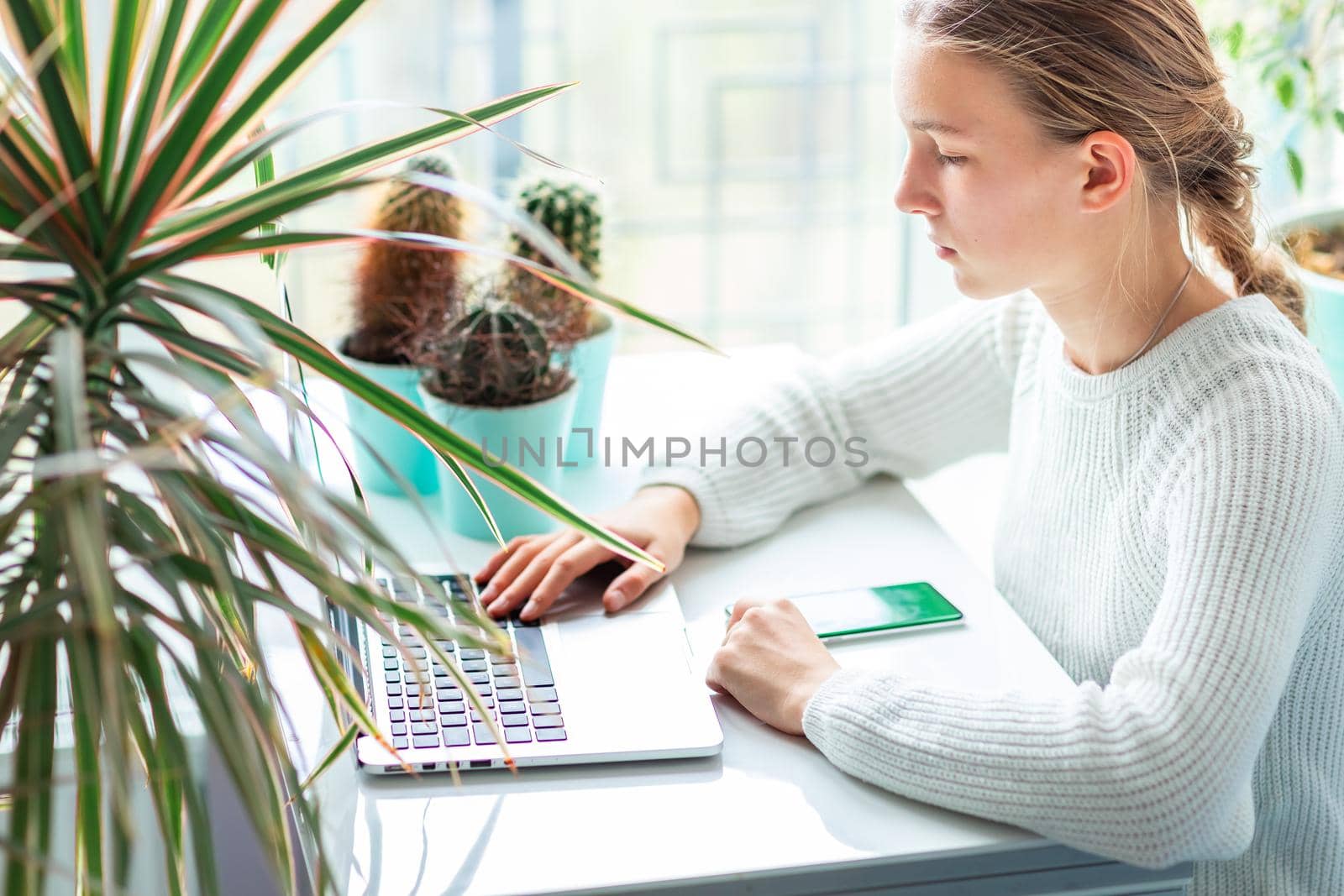 Beautiful teenage young school girl working at home in her room with a laptop studying in a virtual class. Distance education and learning concept during quarantine