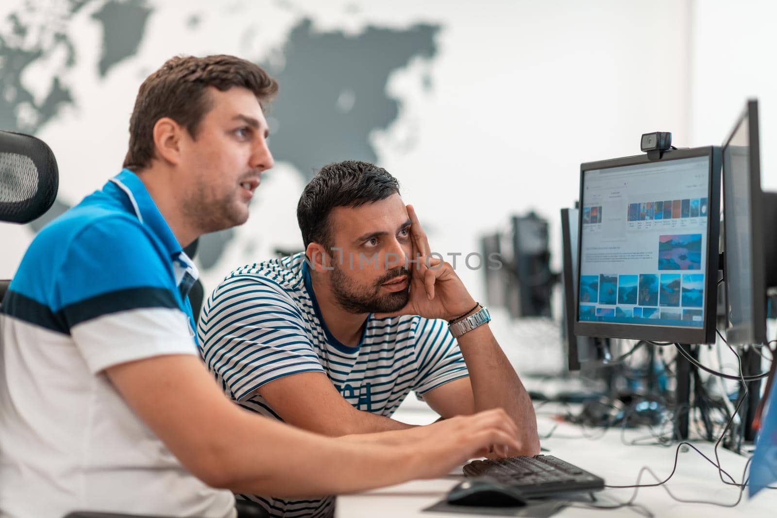 Group of Casual businessmen working on a desktop computer in modern open plan startup office interior. Selective focus. High-quality photo