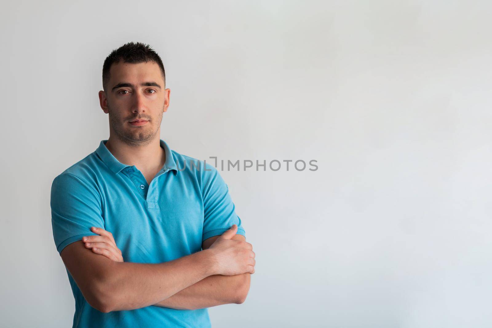 Formal business male portrait. A confident successful casual businessman or manager stands in front of a white background, arms crossed, looking directly at the camera and smiling friendly. High quality photography by dotshock