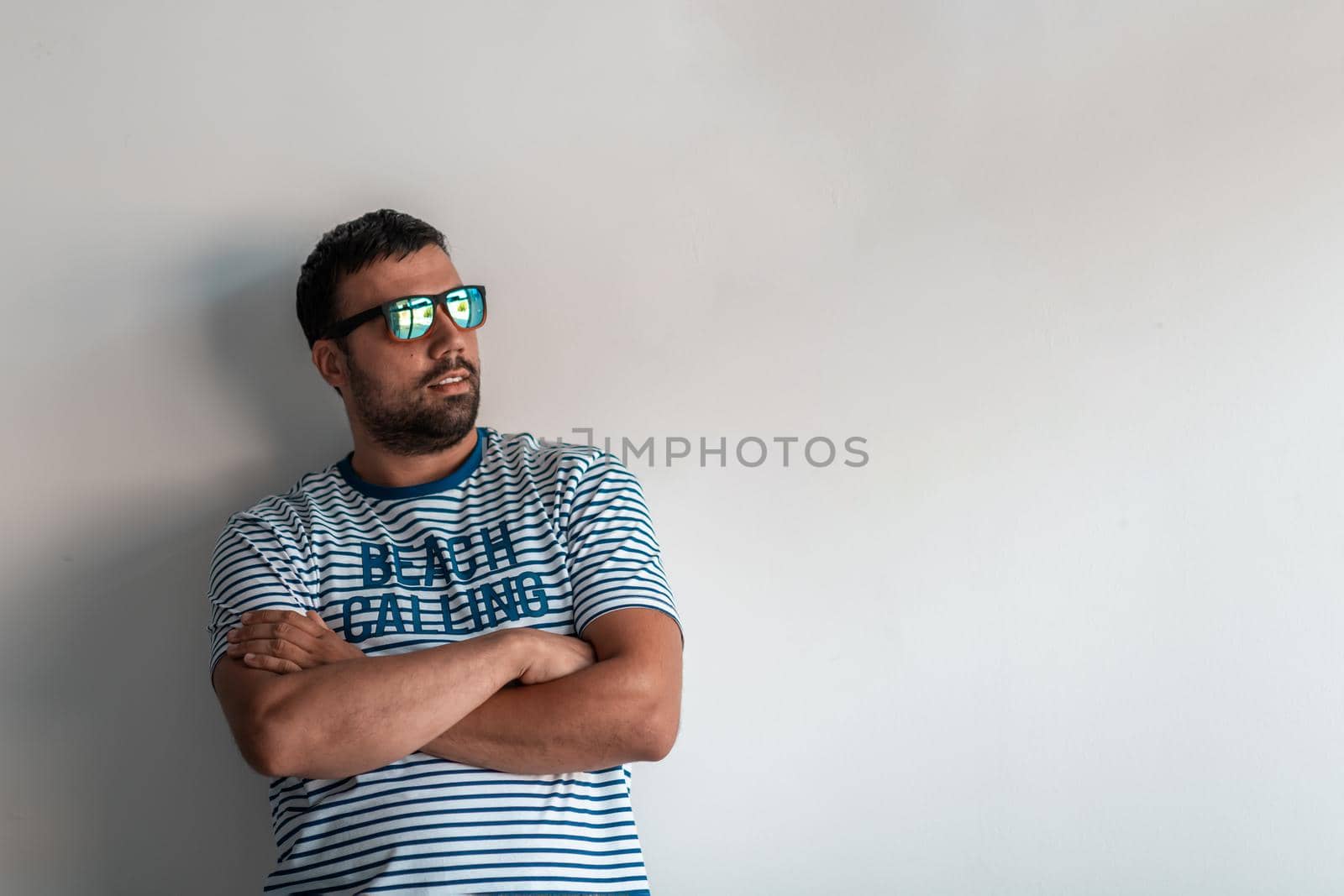 Formal business male portrait. A confident successful casual businessman or manager stands in front of a white background, arms crossed, looking directly at the camera and smiling friendly. High quality photography by dotshock