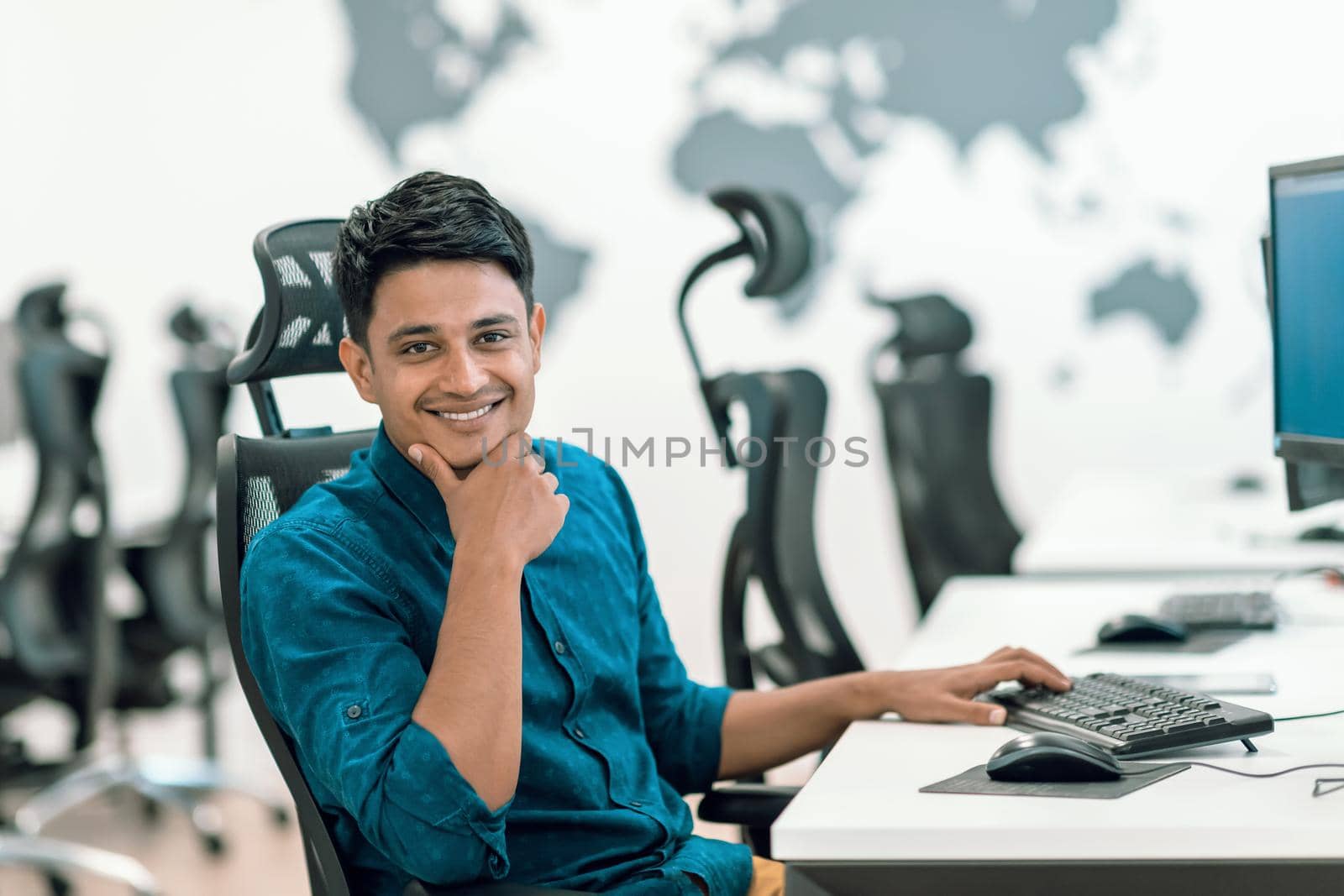 Casual business man working on desktop computer in modern open plan startup office interior. Selective focus by dotshock